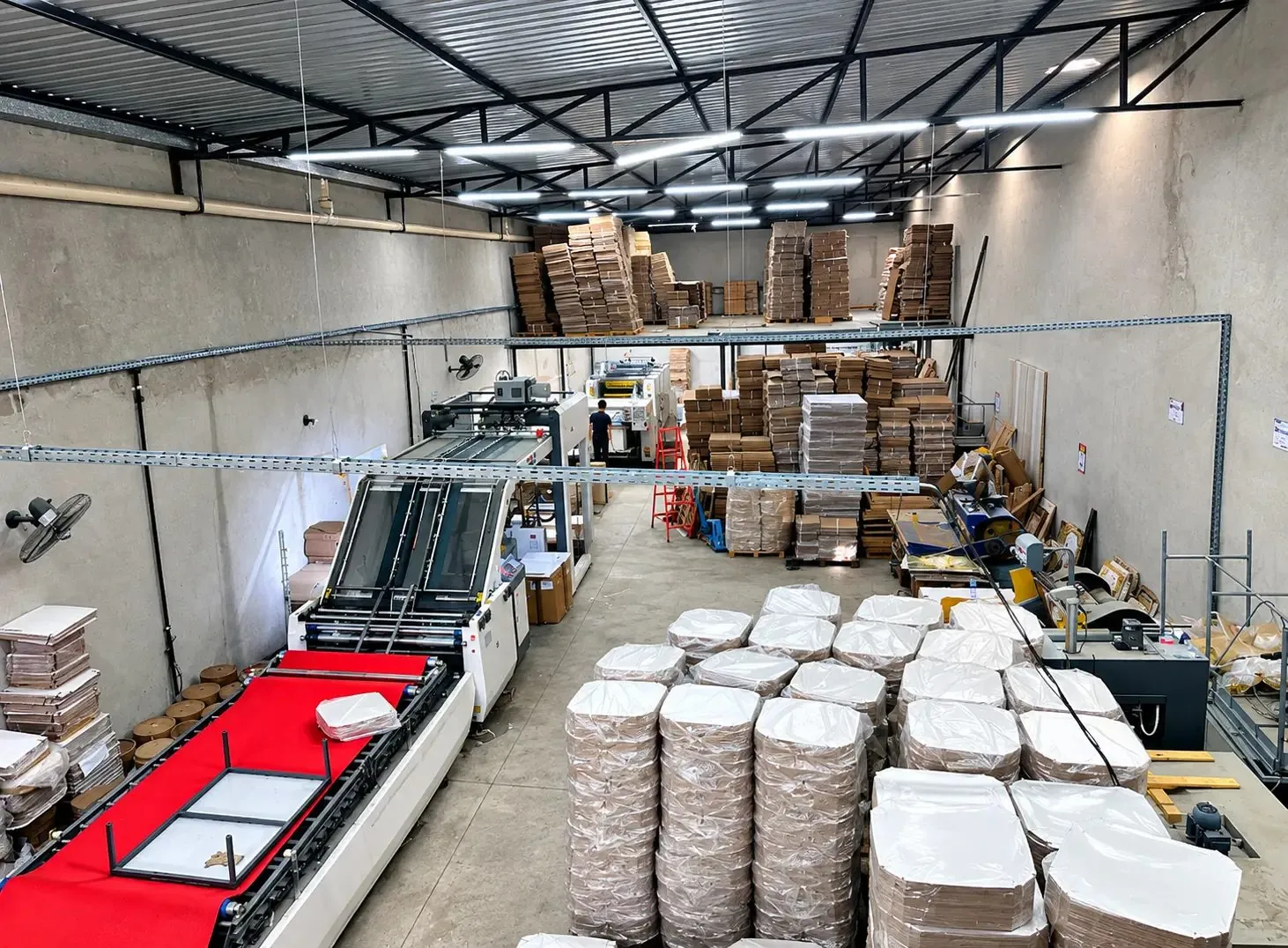 Vista do galpão da Decgraf com máquinas de produção e caixas de pizza prontas